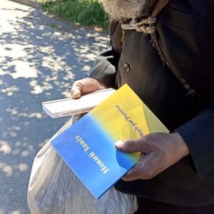 A man receiving food and a Ukrainian New Testament