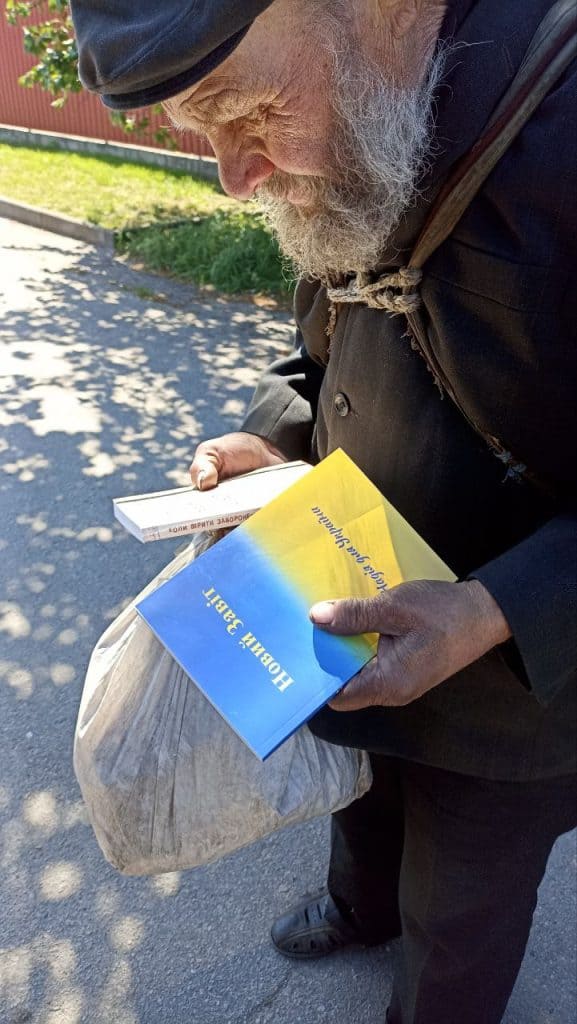 A man receiving food and a Ukrainian New Testament 